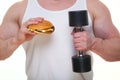 Fat man with a hamburger holds dumbbells isolated on white. The concept of choosing between harmful food and a healthy