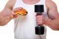 Fat man with a hamburger holds dumbbells on white. The concept of choosing between harmful food and a healthy