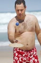 Fat man playing beach tennis
