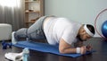 Fat man practicing plank exercise on mat during home workout, will power, goal