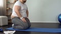 Fat man sitting on knees, resting after exhausted exercises, slimming process Royalty Free Stock Photo