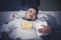Fat man sleeping with junk foods on the bed Royalty Free Stock Photo
