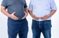 2 fat man are standing and using their hands to hold their belly fat Royalty Free Stock Photo