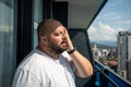 Fat man suffers dying from heat. Guy on balcony under hot summer sun sweats from high temperatures