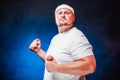 Chubby man with a white bandage on his head lifts two red dumbbells and looks very proud Royalty Free Stock Photo