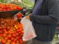 Fat man using bioplastic bag selecting tomatoes at groceries store