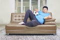 Fat man watching soccer game while lying on sofa Royalty Free Stock Photo