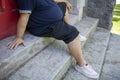 Fat, obese man with diabetes and in ill health outdoors sitting on outdoor stoop