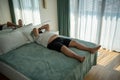 Fat oversize man suffer dying from heat. Lazy, obese overweight guy lies on bed, feels tired in room