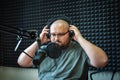 Fat radio presenter or host in radio station studio with headphones and microphone, portrait of working man Royalty Free Stock Photo