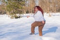 A fat red-haired woman in a white sweatshirt walks through snowdrifts. Royalty Free Stock Photo