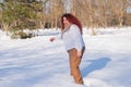 A fat red-haired woman in a white sweatshirt walks through snowdrifts. Royalty Free Stock Photo