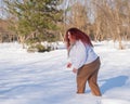 A fat red-haired woman in a white sweatshirt walks through snowdrifts. Royalty Free Stock Photo