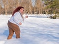 A fat red-haired woman in a white sweatshirt walks through snowdrifts. Royalty Free Stock Photo