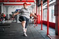 Fat sweaty woman doing exercise with rope in gym