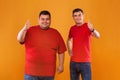 Fat and thin guys in red t-shirt. Two men with different complexion isolated on a yellow background. Ectomorph and Royalty Free Stock Photo