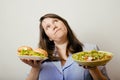 Fat white woman having choice between hamburger and salad close up, unhealth fast food