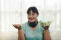 Fat woman Asian in sportswear to holding shows Junk food and fresh salad in decides eating. choosing healthy food such as fresh Royalty Free Stock Photo