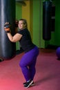 Fat woman beats a punching bag in the gym. Way to lose weight.