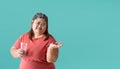 Fat woman bored hand holding pills  isolated on blue background. Royalty Free Stock Photo