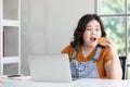 Fat woman eating a hamburger while working from home Royalty Free Stock Photo