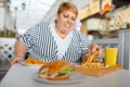 Fat woman eating high calorie food in mall