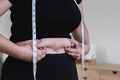 Fat woman, fat belly, obesity, fat woman& x27;s hand holding excessive belly fat with measuring tape, female lifestyle Royalty Free Stock Photo