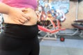 Fat woman holding excessive fat belly lower back, overweight fatty belly at fitness gym. Diet lifestyle, weight loss, stomach Royalty Free Stock Photo