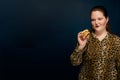 Fat woman in a leopard print blouse with a hamburger in her hand.