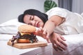 Fat woman lying on the bed eating a hamburger