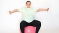 Fat woman making exercises with dumbbells on a fitness ball