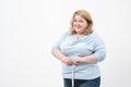 A fat woman measures her waist with a measuring tape in casual clothing on a white background. Royalty Free Stock Photo