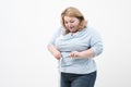 A fat woman measures her waist with a measuring tape in casual clothing on a white background. Royalty Free Stock Photo