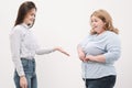 A fat woman measures her waist with a measuring tape in casual clothing on a white background. Royalty Free Stock Photo