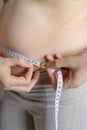 A fat woman measures her waist with a measuring tape, close-up.Weight loss, obesity. Woman after childbirth. Royalty Free Stock Photo