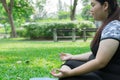 Fat woman practicing yoga and Meditation on green grass in the park. health concept and copy space