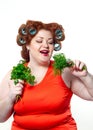 Fat woman with sensuality red lipstick in curlers on a diet holding parsley and dill Royalty Free Stock Photo