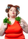 Fat woman with sensuality red lipstick in curlers on a diet holding parsley and dill Royalty Free Stock Photo