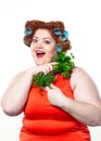 Fat woman with sensuality red lipstick in curlers on a diet holding parsley and dill Royalty Free Stock Photo