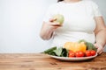 Fat woman snacking with fruits and vegetables Royalty Free Stock Photo