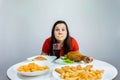 Fat woman with a taped mouth sits at a table with fast food Royalty Free Stock Photo