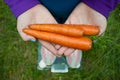 Fat woman wants to lose weight holds in hands folded boat three large orange fresh carrots Royalty Free Stock Photo
