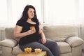 Fat woman watching series at tv eating junk food Royalty Free Stock Photo