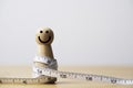 Fat wooden figure with measuring tape for happy diet and weight loss concept
