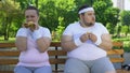 Fat young couple eating hamburgers, addicted to junk food, lack of willpower