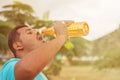 Fat young man drinking water from bottle outdoor - Thirsty obese man drinking water after exercise.