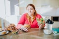 Fat young woman in kitchen sitting and eating food. Healthy lifestyle. Looking at burger and bowl salad. Body positive