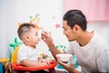 Father acting Mom feeding his son baby 1 year old on chair Royalty Free Stock Photo