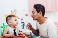 Father acting Mom feeding his son baby 1 year old on chair Royalty Free Stock Photo