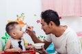 Father acting Mom feeding his son baby 1 year old on chair Royalty Free Stock Photo